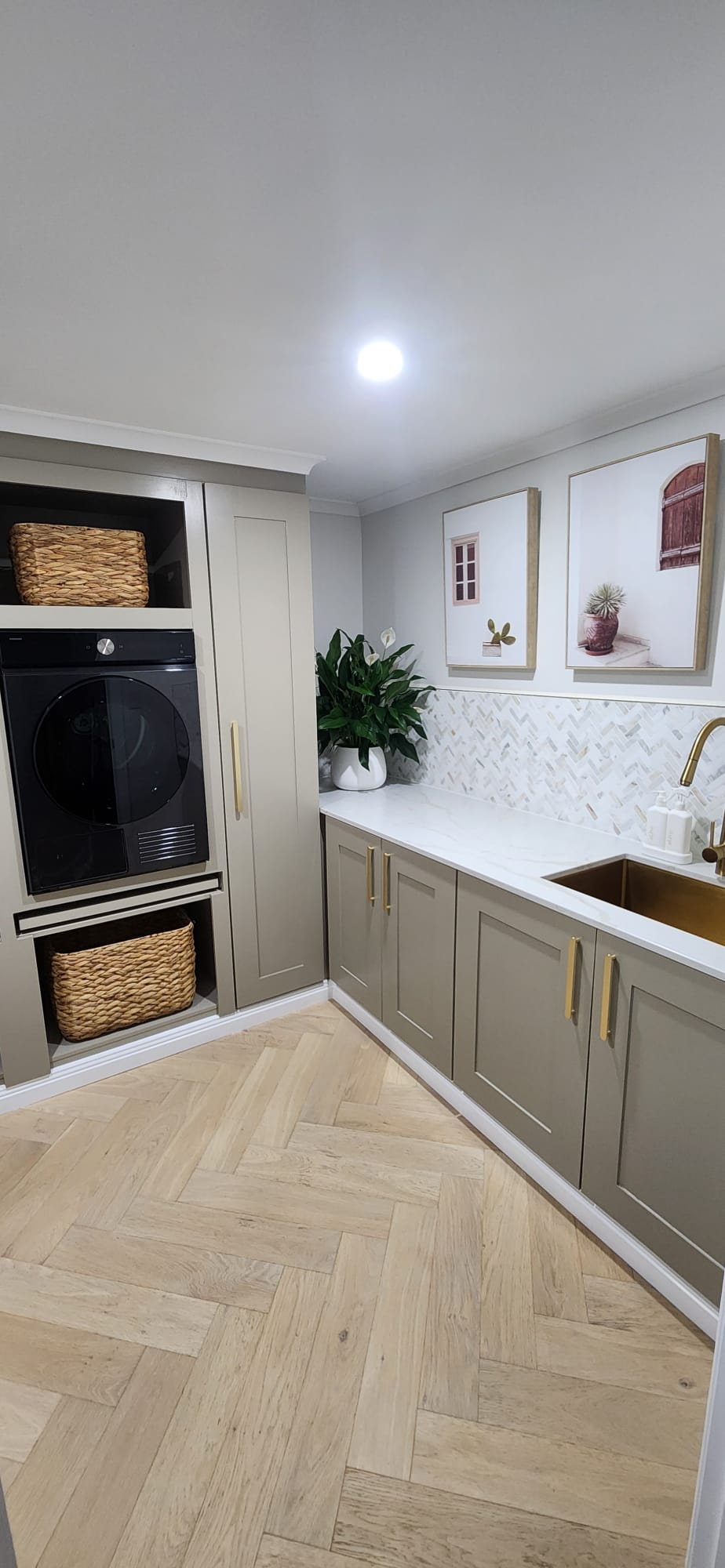 Completed laundry renovation with built-in appliances and herringbone oak floor